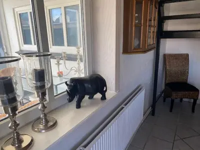a statue of a pig sitting on a window sill at Dejlig gårdhave 5 soveværelser in Harboør