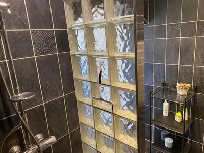 a shower with a glass block wall in a bathroom at Dejlig gårdhave 5 soveværelser in Harboør