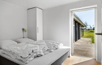 a white bedroom with a bed and a sliding glass door at 3 Bedroom Pet Friendly Home In Løkken in Løkken