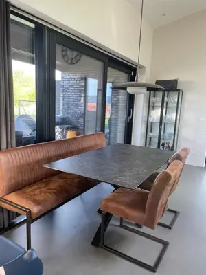 a dining room with a table and leather chairs at Moderne bynært hus in Holstebro