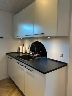 a kitchen with white cabinets and a black counter top at Nyrenoveret,hyggeligt og centralt hus in Holstebro