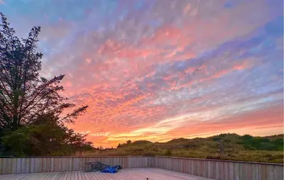 a sunset over a deck with a bench on a fence at 4 Bedroom Cozy Home In Saltum in Saltum