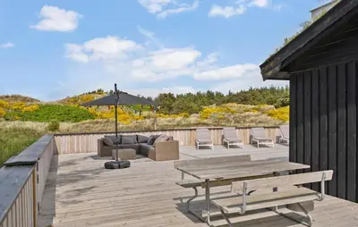 a wooden deck with a table and chairs and an umbrella at 4 Bedroom Cozy Home In Saltum in Saltum