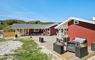 a house with a deck and a red building at 3 Bedroom Beautiful Home In Blokhus in Blokhus