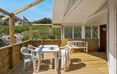 a wooden deck with a table and chairs on it at 3 Bedroom Beautiful Home In Blokhus in Blokhus