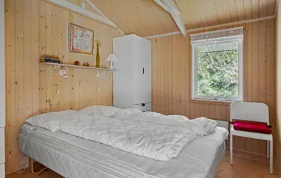 a bedroom with a large bed in a room with wooden walls at 3 Bedroom Beautiful Home In Blokhus in Blokhus