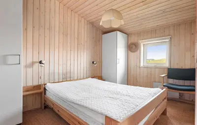 a bedroom with a bed and a chair and a window at Stunning Home In Blokhus With Wifi in Blokhus