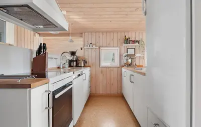 a kitchen with white appliances and wooden walls at Stunning Home In Blokhus With Wifi in Blokhus
