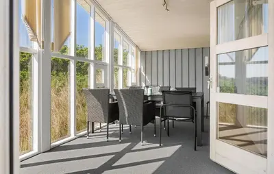 a dining room with a table and chairs and windows at Stunning Home In Blokhus With Wifi in Blokhus