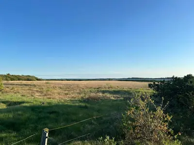 a field with a wire fence in the middle of a field at Summer House With Fields And Fjord Views in Thyholm
