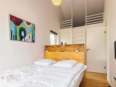 a bedroom with a white bed with a wooden headboard at 4 star holiday home in Brovst in Brovst