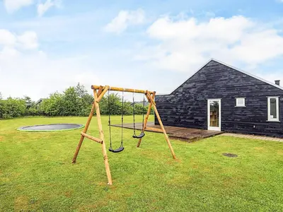 a swing set in a yard in front of a house at 4 star holiday home in Brovst in Brovst