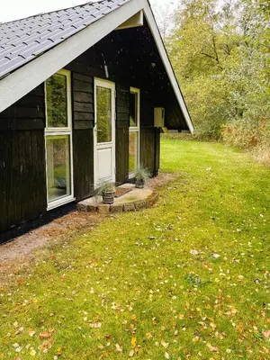 a black house with a porch and a door at Simple Cottage Close To Limfjorden in Åbybro