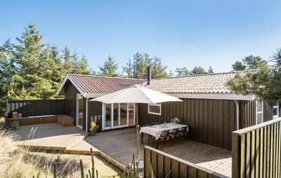 a house with a wooden deck with an umbrella at Stunning Home In Saltum With Wifi in Saltum
