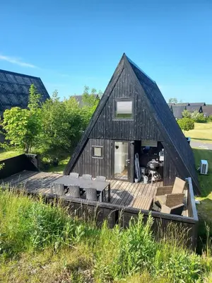 a large black barn with a deck and benches at Holiday home golf house in beautiful Himmerland Farsø in Farsø
