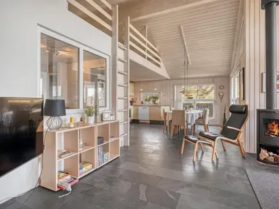 a living room with a fireplace and a dining room at Holiday Home Elni - 350m from the sea by Interhome in Blokhus