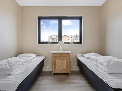 two beds in a room with a table and a window at Holiday Home Stjerne - 300m to the fjord by Interhome in Lemvig