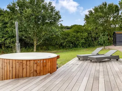 a hot tub on a wooden deck with two chairs at Holiday Home Stjerne - 300m to the fjord by Interhome in Lemvig