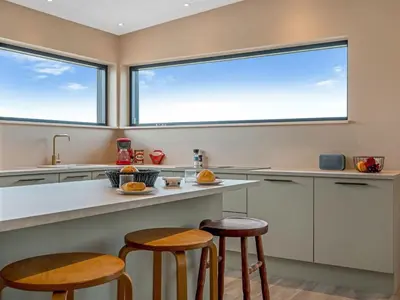 a kitchen with two large windows and two stools at Holiday Home Stjerne - 300m to the fjord by Interhome in Lemvig