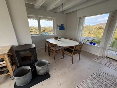 a living room with a table and a fireplace at Holiday Home Wighlek - 800m from the sea by Interhome in Snedsted