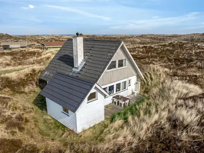 a small white house with a black roof in a field at Holiday Home Wighlek - 800m from the sea by Interhome in Snedsted