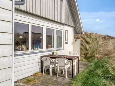 a table and chairs sitting on a deck next to a building at Holiday Home Wighlek - 800m from the sea by Interhome in Snedsted