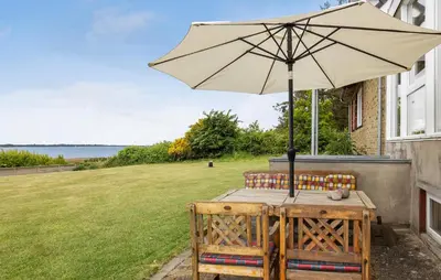 a wooden table with an umbrella and two chairs at Nice Home In Roslev With House Sea View in Roslev