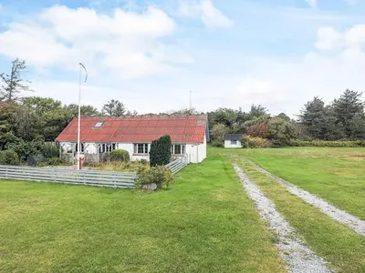 a white house with a red roof in a field at 6 person holiday home in Vestervig in Vestervig