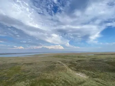 an open field with a cloudy sky and water at 4 person holiday home in Vestervig in Vestervig