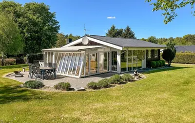 a white house with a table and chairs in a yard at 2 Bedroom Cozy Home In Farsø in Farsø