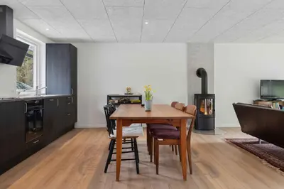a kitchen with a wooden table and some chairs at Holiday Home In 1St Row By The Limfjord in Thyholm