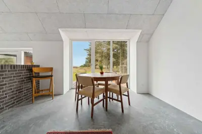 a dining room with a table and chairs and a window at Holiday Home In 1St Row By The Limfjord in Thyholm