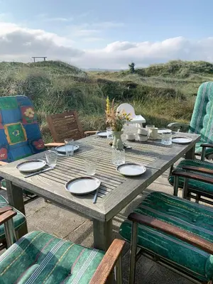 a wooden table with plates and flowers and chairs at Cosy, Traditional Summer House Close To The North Sea in Fjerritslev