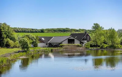 a house next to a river with a house at Lovely Home In Nibe With Lake View in Nibe