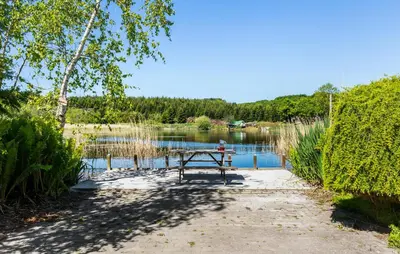 a picnic table sitting in front of a lake at Lovely Home In Nibe With Lake View in Nibe
