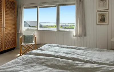a bedroom with a bed and a chair and windows at 3 Bedroom Stunning Home In Øster Assels in Øster Assels