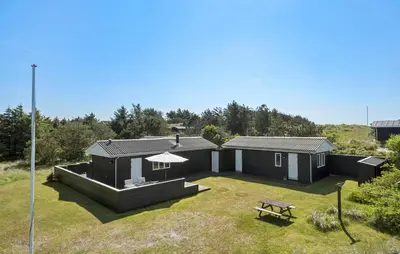 a black house with a picnic table in a yard at Amazing Home In Løkken With Wifi in Løkken
