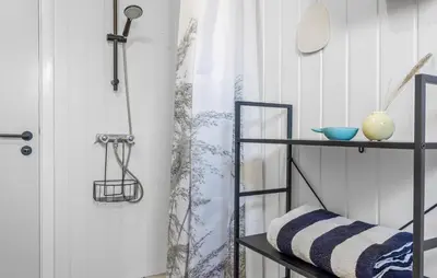 a bathroom with a shower curtain and a shelf at Amazing Home In Løkken With Wifi in Løkken