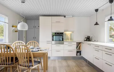 a kitchen with white cabinets and a table and chairs at Amazing Home In Løkken With Wifi in Løkken