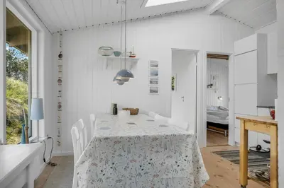 a white dining room with a table and chairs at Well-Maintained Holiday Home With Outdoor Shower And 5-Person Outdoor Hot Tub, Close To The North Sea In Klitmøller in Klitmøller