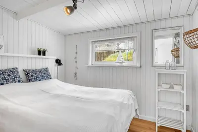 a white bedroom with a bed and two windows at Beautifully Renovated Holiday Home With Covered Terrace And Wood-Burning Stove, Close To The North Sea In Thy in Sønder Vorupør