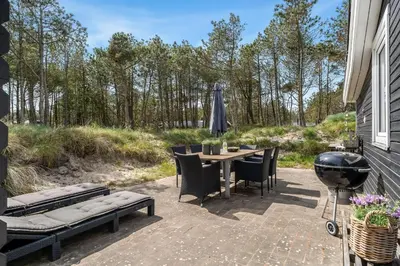 a patio with a grill and a table and chairs at Beautifully Renovated Holiday Home With Covered Terrace And Wood-Burning Stove, Close To The North Sea In Thy in Sønder Vorupør