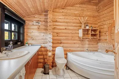a bathroom with a tub and a toilet and a sink at Well-Maintained Log House With Hot Tub, Sauna And Covered Terrace In Thy