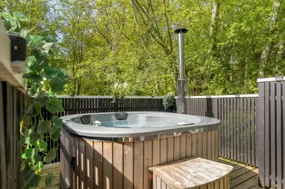 a hot tub on a deck with a wooden fence at Lovely Renovated Holiday Home With A Wilderness Bath And Fenced Grounds in Vesløs