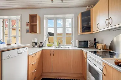 a kitchen with wooden cabinets and white appliances at Charming Townhouse From 1877, Located In The Middle Of Løgstør Only 100 Meters From The Harbor in Løgstør