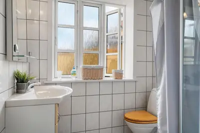 a white bathroom with a toilet and a sink at Charming Townhouse From 1877, Located In The Middle Of Løgstør Only 100 Meters From The Harbor in Løgstør