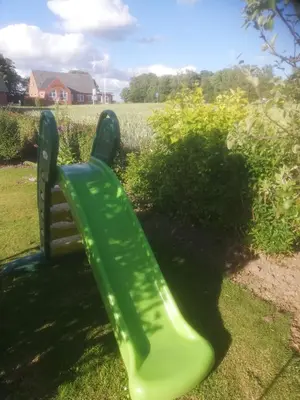 a green park bench sitting in the grass at Holiday Home Kirkeby Feriehus in Roslev