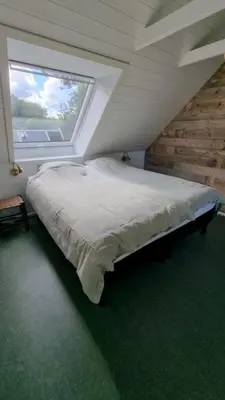 a bedroom with a large bed with a window at Koppes Mølle B&B - naturnær overnatning in Borup