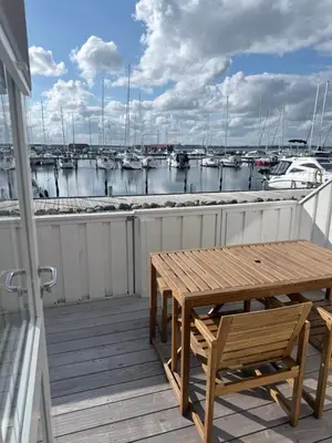 a wooden deck with a table and chairs and boats at Cozy harbor house in Nibe in Nibe
