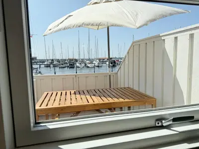 a bench on a balcony with a view of a marina at Cozy harbor house in Nibe in Nibe